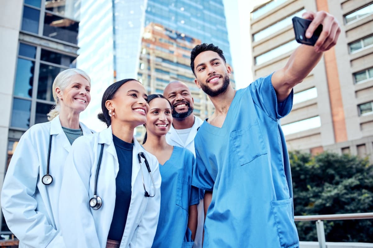 Ärzte und Pflegekräfte machen Selfie vor Klinikgebäude
